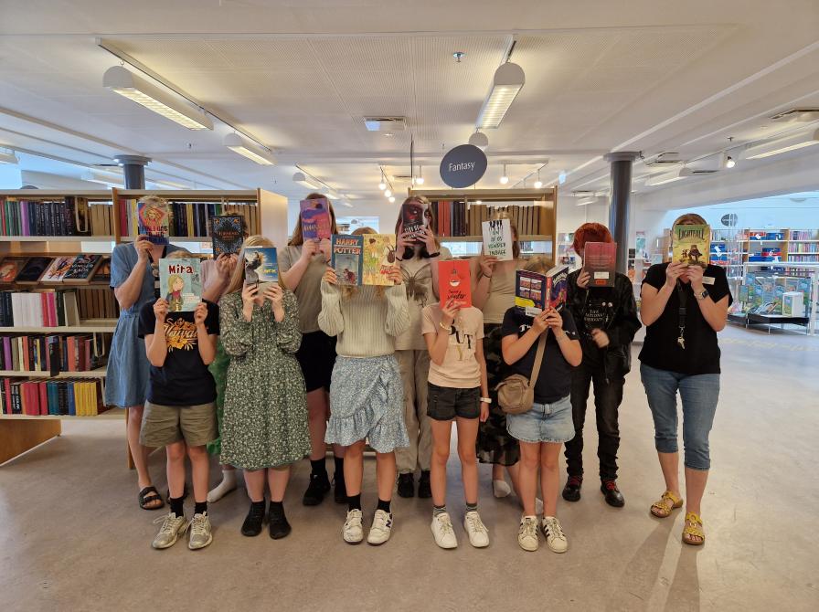 Børn der holder bøger med forsiden fremad foran deres ansigter